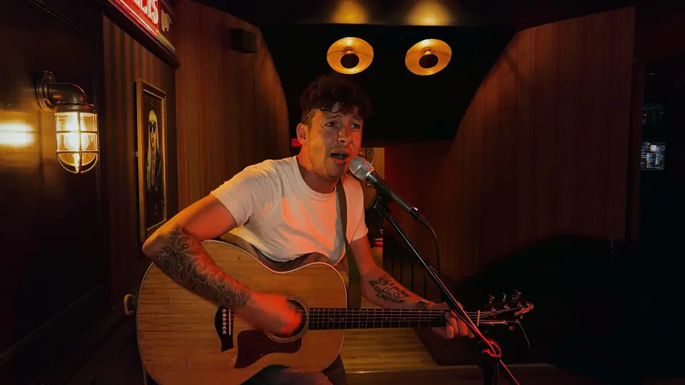 The same pub frame on the clean automatic grade — the singer lit naturally, the dark room held honest
